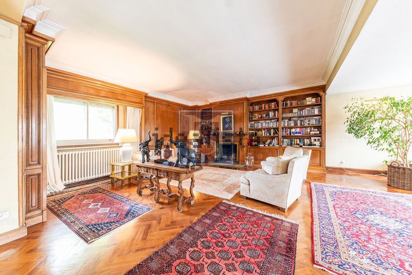 Gran salón clásico con biblioteca y chimenea